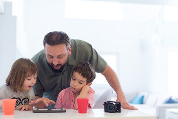 Image showing single father at home with two kids playing games on tablet