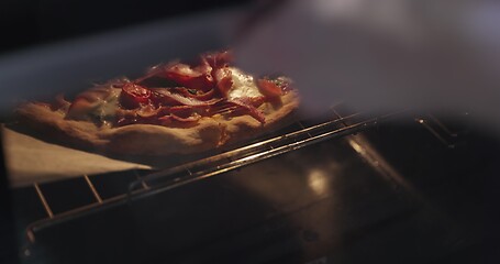 Image showing Homemade pizza being checked on in oven