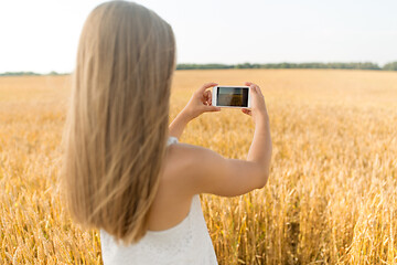 Image showing girl taking picture by smartphone on cereal field