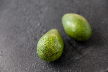 Image showing two avocados on wet slate stone background