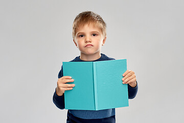 Image showing displeased little boy reading book