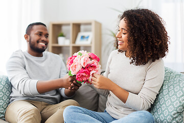 Image showing happy couple with bunch of flowers at home