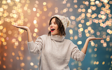 Image showing young woman in winter hat holding something