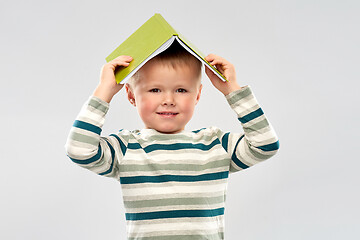 Image showing portrait of smiling boy with book on head