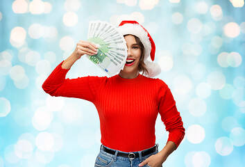 Image showing happy woman in santa hat with money on christmas