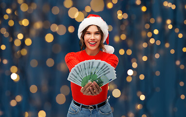 Image showing happy woman in santa hat with money on christmas