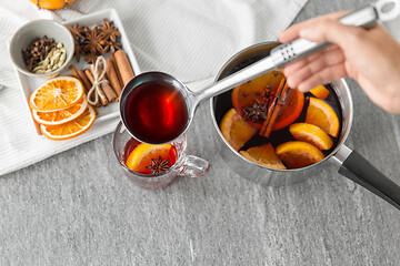 Image showing hand with ladle pouring hot mulled wine to glass