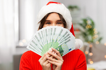 Image showing happy woman in santa hat with money on christmas