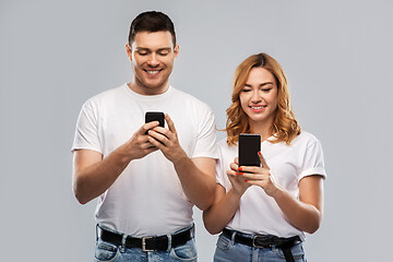 Image showing happy couple in white t-shirts with smartphones