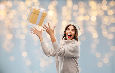 Image showing young woman in winter hat catching gift box