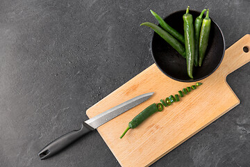 Image showing green chili peppers and knife on cutting board