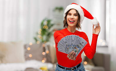 Image showing happy woman in santa hat with money on christmas