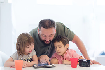 Image showing single father at home with two kids playing games on tablet