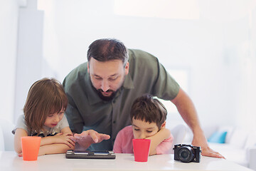 Image showing single father at home with two kids playing games on tablet