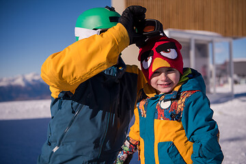 Image showing father preparing his little son for the first time on a snowboar