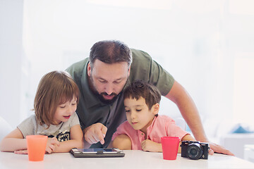 Image showing single father at home with two kids playing games on tablet