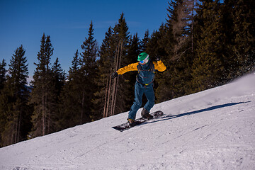 Image showing snowboarder running down the slope and ride free style