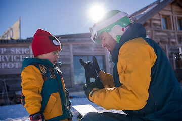 Image showing father preparing his little son for the first time on a snowboar