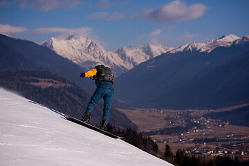 Image showing snowboarder running down the slope and ride free style