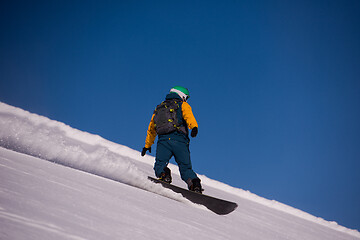 Image showing snowboarder running down the slope and ride free style