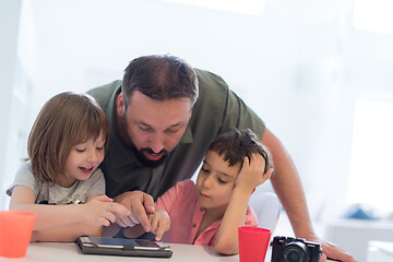 Image showing single father at home with two kids playing games on tablet