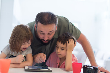 Image showing single father at home with two kids playing games on tablet