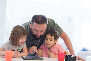 Image showing single father at home with two kids playing games on tablet