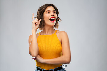 Image showing happy smiling young woman pointing finger up