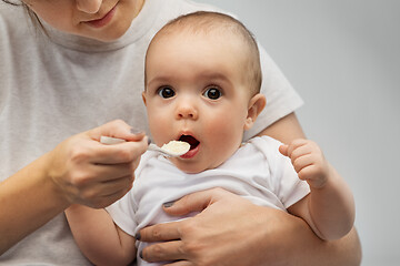 Image showing close up of mother with spoon feeding little baby