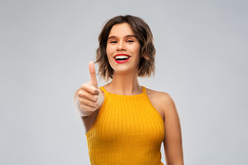 Image showing happy smiling young woman showing thumbs up