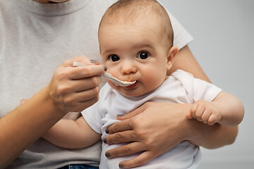 Image showing close up of mother with spoon feeding little baby