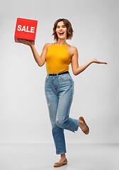 Image showing happy smiling young woman posing with sale sign