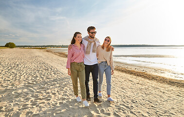 Image showing happy friends walking along summer beach