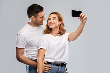 Image showing happy couple in white t-shirts taking selfie