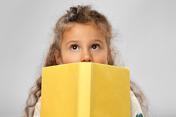 Image showing little girl hiding behind yellow book