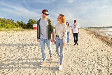 Image showing happy friends walking along summer beach