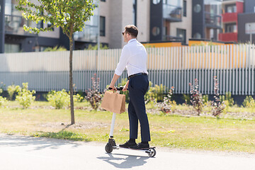 Image showing businessman with takeaway paper bag riding scooter