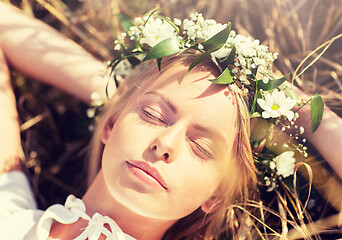 Image showing happy woman in wreath of flowers lying on straw