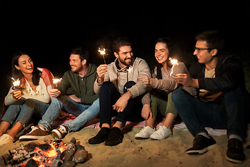 Image showing happy friends with sparklers at camp fire at night