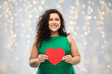 Image showing happy woman holding red heart over lights