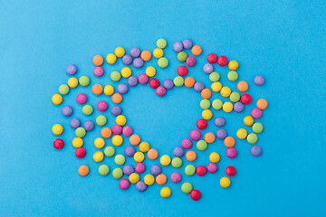 Image showing candy drops in shape of heart on blue background