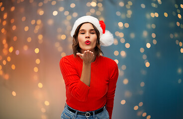 Image showing woman in santa hat sending air kiss on christmas