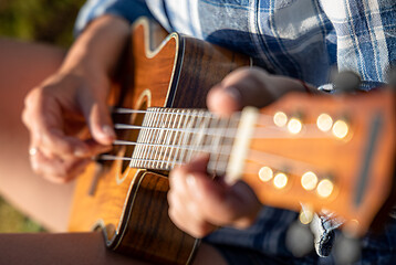 Image showing Woman at sunset playing the ukulele