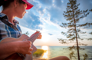 Image showing Woman at sunset playing the ukulele