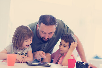 Image showing single father at home with two kids playing games on tablet