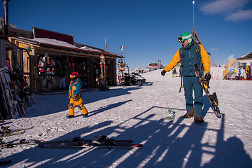 Image showing father preparing his little son for the first time on a snowboar