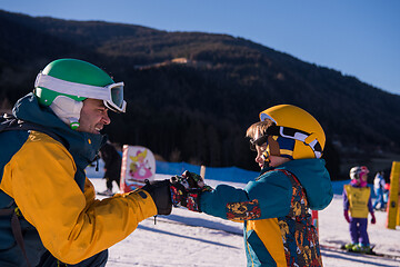 Image showing father preparing his little son for the first time on a snowboar