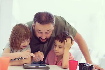 Image showing single father at home with two kids playing games on tablet