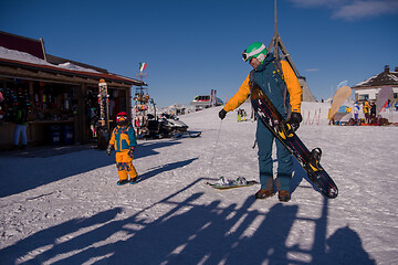 Image showing father preparing his little son for the first time on a snowboar