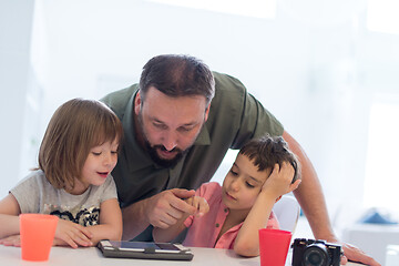 Image showing single father at home with two kids playing games on tablet